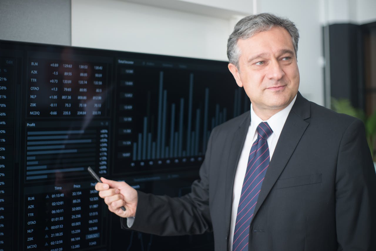 Services Professional man in suit reviewing financial charts on monitor, showcasing stock market trends.